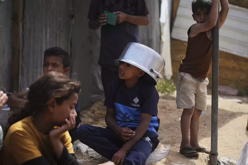 Palestinian children wait to receive donated food at a distribution center in Khan Younis, Gaza Strip, Monday, April 21, 2025. (AP Photo/Abdel Kareem Hana)
