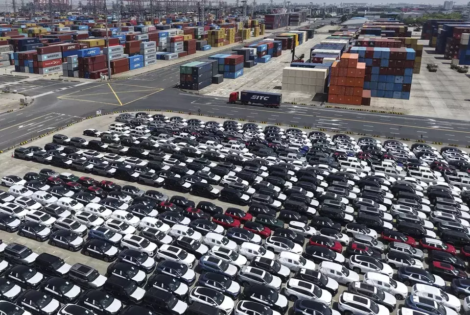 A truck moves past new vehicles for export at a port in Shanghai, China, on Sunday, April 27, 2025. (Chinatopix Via AP)