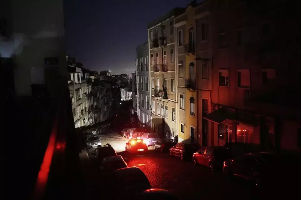 A car drives down an unlit street in Lisbon during a nationwide power outage, Monday night, April 28, 2025. (AP Photo/Armando Franca)