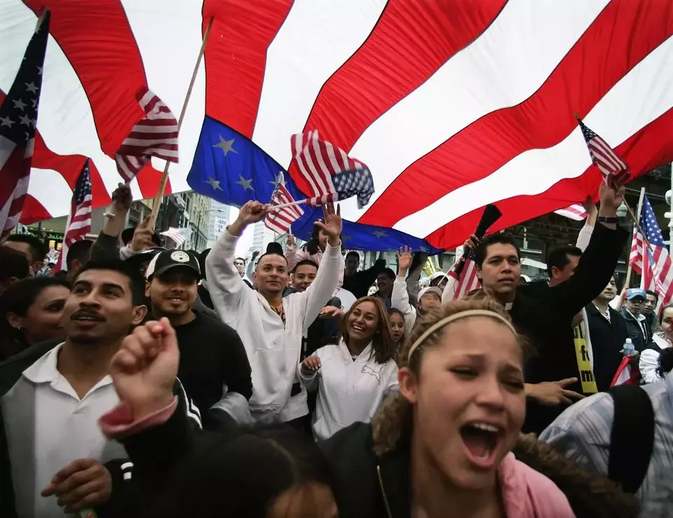Participants in an immigration rights rally walk under a giant American flag during a march through downtown Chicago, May 1, 2006. (AP Photo/M. Spencer Green)