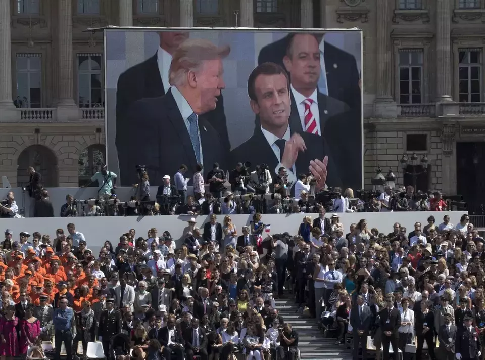 FILE - President Donald Trump, pictured on screen from left, French President Emmanuel Macron, and White House Chief of Staff Reince Priebus watch a Bastille Day parade on the Champs Elysees avenue in Paris, July 14, 2017. (AP Photo/Carolyn Kaster, File)