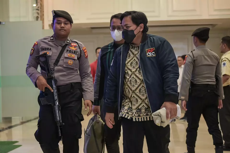 An armed policeman escorts two investigators of the Corruption Eradication Commission (KPK) during a search at the Manpower Ministry building in Jakarta, Tuesday, May 5, 2025. (Antara Photo/Fauzan)