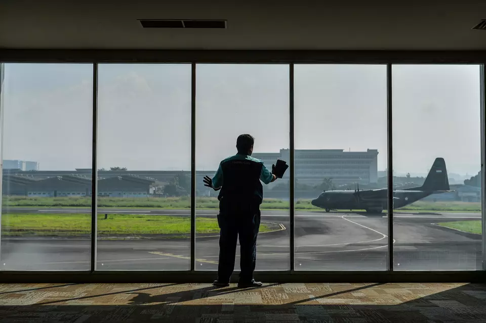 A worker cleans glass windows at the quiet departure terminal of Husein Sastranegara Airport in Bandung, West Java, Wednesday, June 25, 2025. (Antara Photo/Raisan Al Farisi)