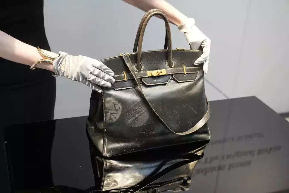 An auction officer displays the original Birkin bag created by Hermes for Jane Birkin in 1984, prior to its auction on Thursday, July 10, 2025, in Paris. (AP Photo/Michel Euler)