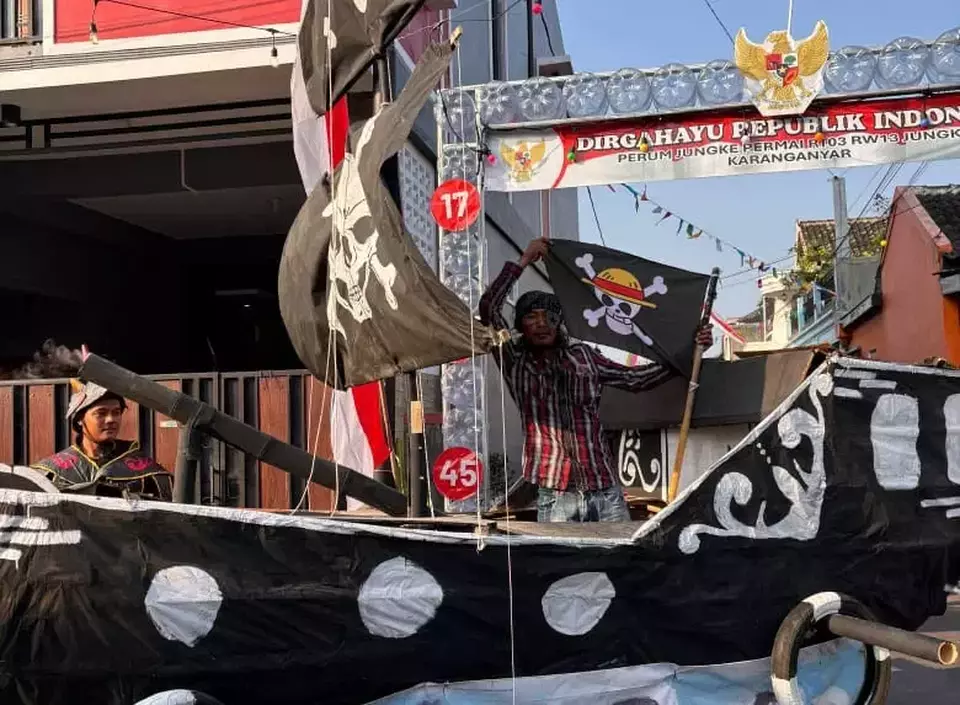 A resident of Karanganyar, Central Java holds up a Jolly Roger flag from the anime One Piece during their village parade on Sunday, Aug. 4, 2025. (beritasatu.com)