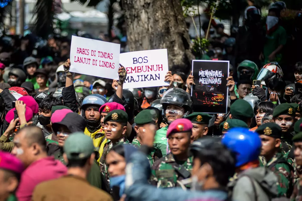 Online taxi drivers hold up posters in front of the Mobile Brigade Corps headquarters in Jakarta on August 29, 2025. The rally slams police brutality after fellow driver Affan Kurniawan gets run over by a police vehicle. (Antara Photo/Putra M Akbar)