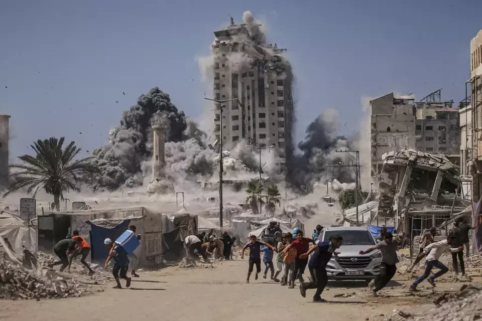 Palestinians run for cover during an Israeli airstrike on a high-rise building in Gaza City, Friday, Sept. 5, 2025, after the Israeli army issued a warning. (AP Photo/Yousef Al Zanoun)