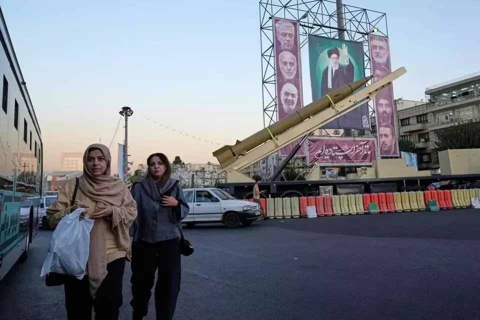 People walk past a domestically-built missile 