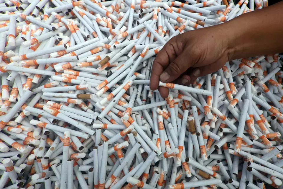 A law enforcement officer displays thousands of illegal cigarettes scheduled to be destroyed by the West Java Customs Office at Pakansari Stadium, Bogor Regency, West Java, Tuesday, Oct. 21, 2025. (Antara Photo/Yulius Satria Wijaya)