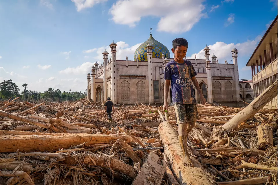 A boy walks along the logs of wood at the Darul Mukhlishin Islamic Boarding School in the flood-hit Aceh on Dec. 5, 2025. (Antara Photo/Erlangga Bregas Prakoso)