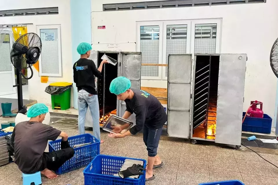 Workers clean and load metal food trays into a large drying oven at the SPPG Sukamantri in Bogor, where the equipment is used to sanitize and prepare containers for daily meal production. (Photo Courtesy of BGN)
