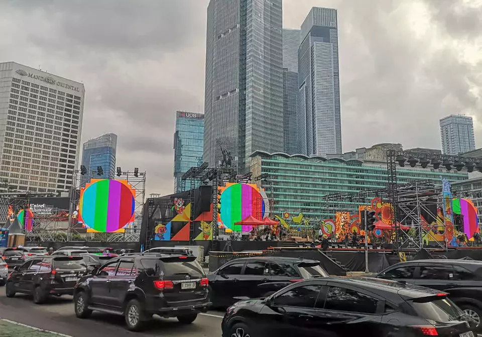 Motorists pass near a stage set up for New Year's Eve celebrations at the Hotel Indonesia roundabout in Jakarta, Tuesday (Dec. 30, 2023). The Jakarta provincial government holds the 2025 New Year's Eve celebration featuring music performances, drone video mapping, interfaith prayers and a donation drive for disaster victims across Indonesia. (Beritasatu Photo/Joanito De Saojoao)