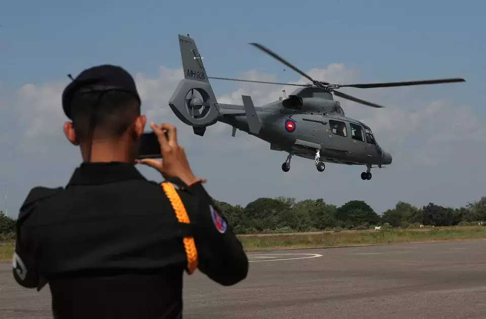 In this photo released by Agence Kampuchea Press (AKP), a helicopter expected to carry released Cambodian soldiers after being captured and held by Thailand flies heading to Phnom Penh International Airport in Phnom Penh, Cambodia, Wednesday, Dec. 31, 2025. (AKP via AP)