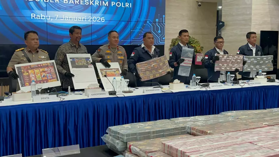 Officers from the National Police's Cyber Crime Directorate show a pile of banknotes and other evidence seized from an online gambling syndicate during a news conference at the police headquarters in Jakarta, Wednesday, Jan. 7, 2026. (B-Universe Photo/Muhammad Aulia Rahman)