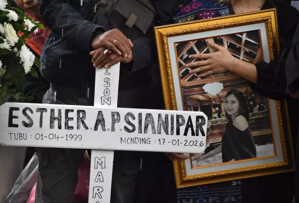 A family member carries a photograph of Esther Aprilita Sianipar during a funeral in Bogor, West Java, on Saturday, Jan. 24, 2026. Esther was a flight attendant on the ATR 42-500 aircraft that crashed in South Sulawesi a week earlier, killing all 10 people on board. (Antara Photo/Arif Firmansyah)