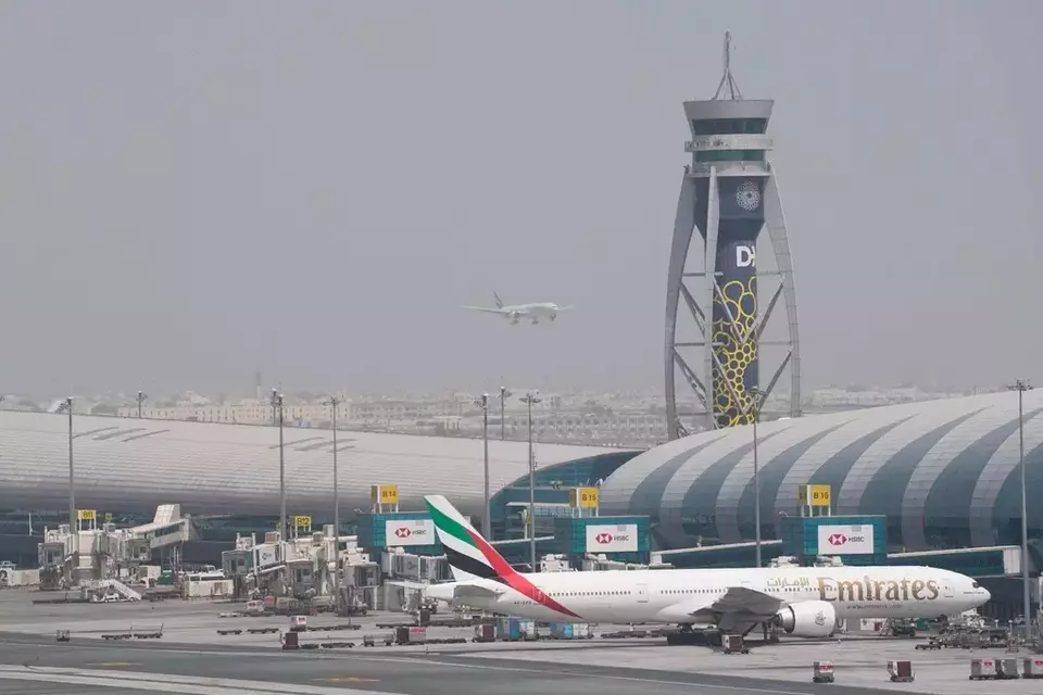 FILE - An Emirates Boeing 777 stands at the gate at Dubai International Airport as another prepares to land on the runway in Dubai, United Arab Emirates, Aug. 17, 2022. (AP Photo/Jon Gambrell, File)