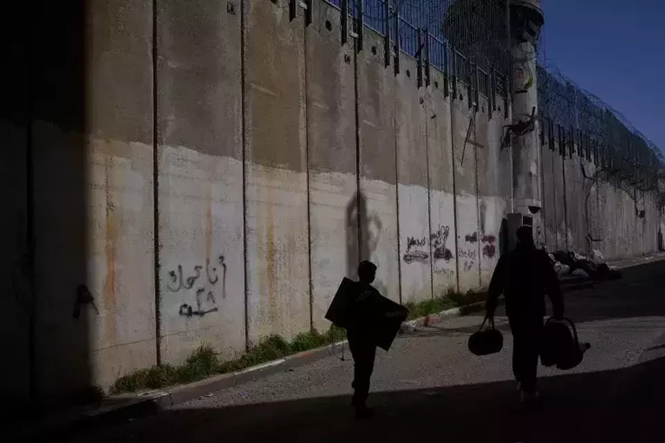 Palestinians walk along the separation barrier between the West Bank and east Jerusalem neighborhood of Beit Hanina on Feb. 15, 2026. (AP Photo/Ohad Zwigenberg)