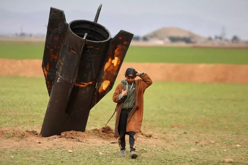 A shepherd boy walks away from an unexploded Iranian projectile that landed in an open field in the outskirts of Qamishli, eastern Syria, Wednesday, March 4, 2026.(AP Photo/Baderkhan Ahmad)

