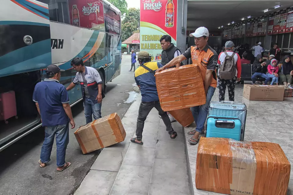 Bus crew load passengers' luggage onto a bus at Kalideres Terminal in West Jakarta on Friday, March 6, 2026. Some travelers depart earlier to avoid the peak Eid homecoming rush and rising ticket prices, with many heading to Sumatra, particularly Aceh and Bengkulu. (BeritaSatu Photo/Joanito De Saojoao).