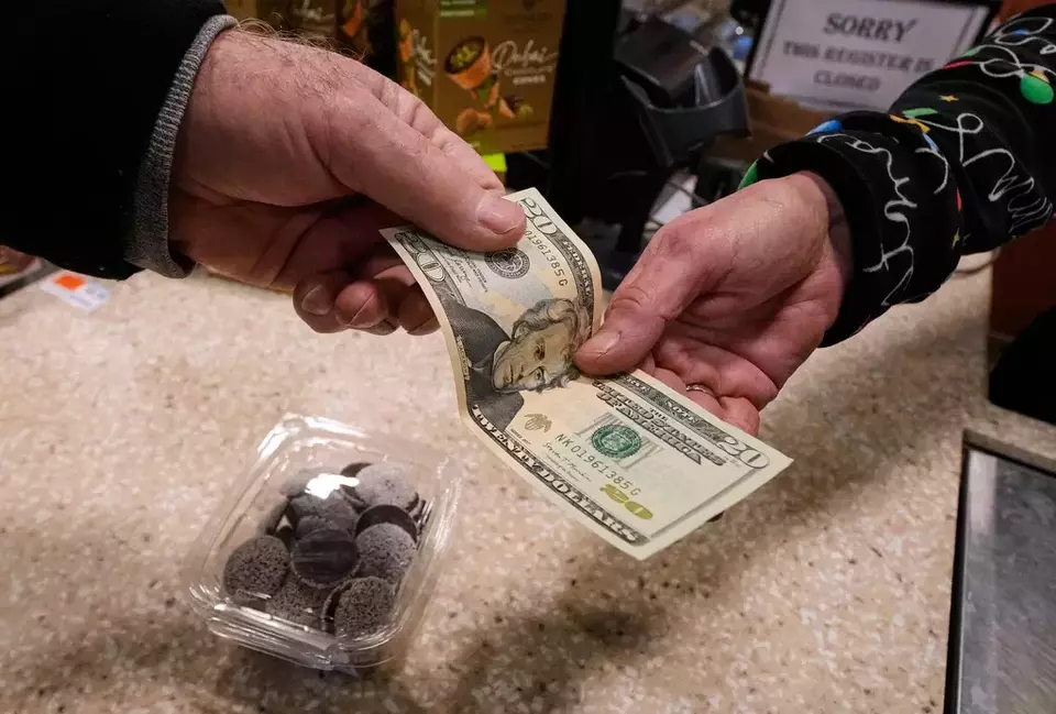 FILE - A shopper pays with cash for a container of candy at a store, Thursday, Dec. 11, 2025, in Salem, New Hampshire. (AP Photo/Charles Krupa, File)