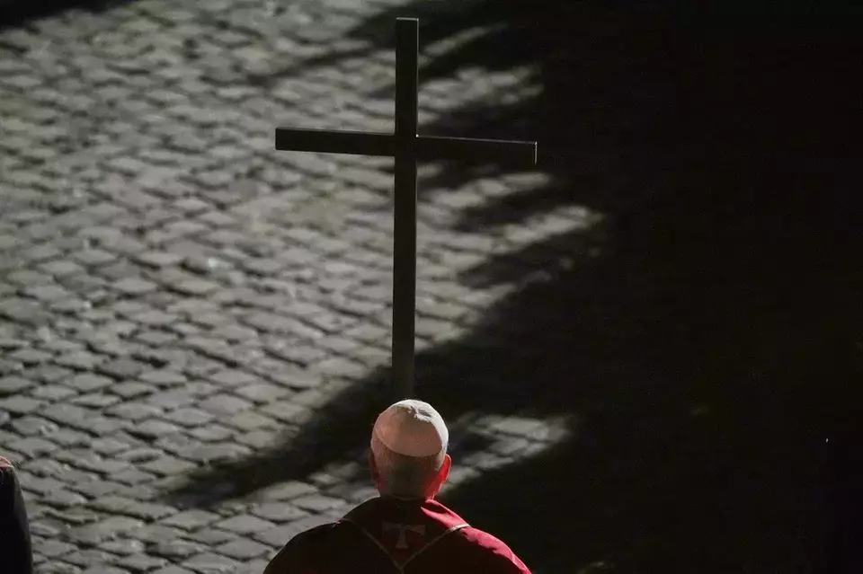 Pope Leo XIV carries a lightweight, 1.5-meter (5-foot) wooden cross during the Via Crucis, the torchlit Good Friday Stations of the Cross procession at the Colosseum in Rome, Friday, April 3, 2026, which symbolically retraces Jesus Christ's steps to his crucifixion on Calvary in Jerusalem. (AP Photo/Alessandra Tarantino)

