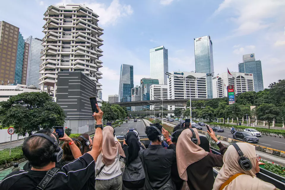 Several tourists take photos and record videos of Jakarta using their devices from the top deck of an open-top bus on Jenderal Sudirman Street in Jakarta on Tuesday, March 24, 2026. (Antara Photo/Rakha Raditya Yahya)