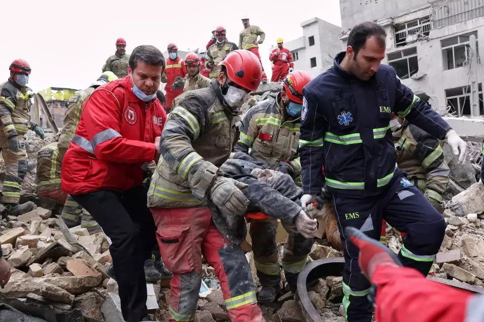 Rescue workers carry a severely injured man after pulling him from the rubble following a strike in southern Tehran, Iran on March 13, 2026. (AP Photo/Sajjad Safari)